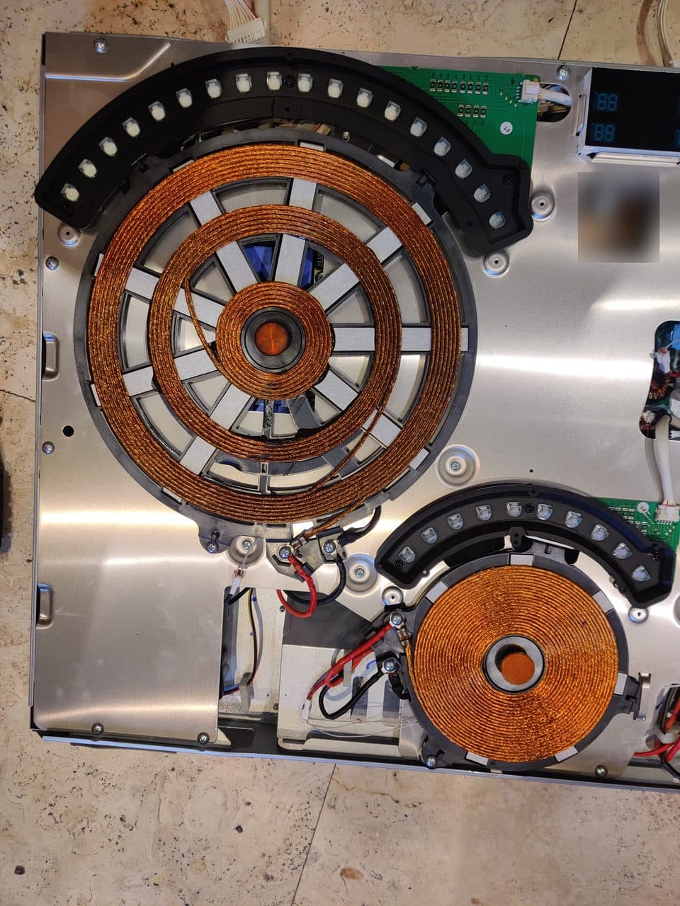 Induction cooktop opened up, showing the copper coils